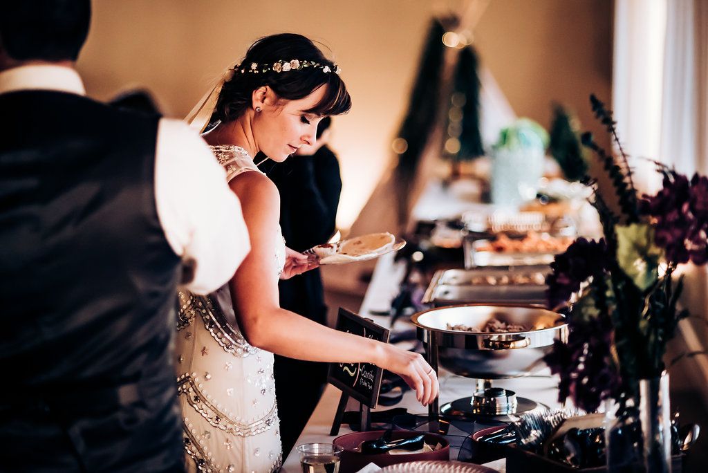 Elegant wedding buffet station with catering staff serving food.