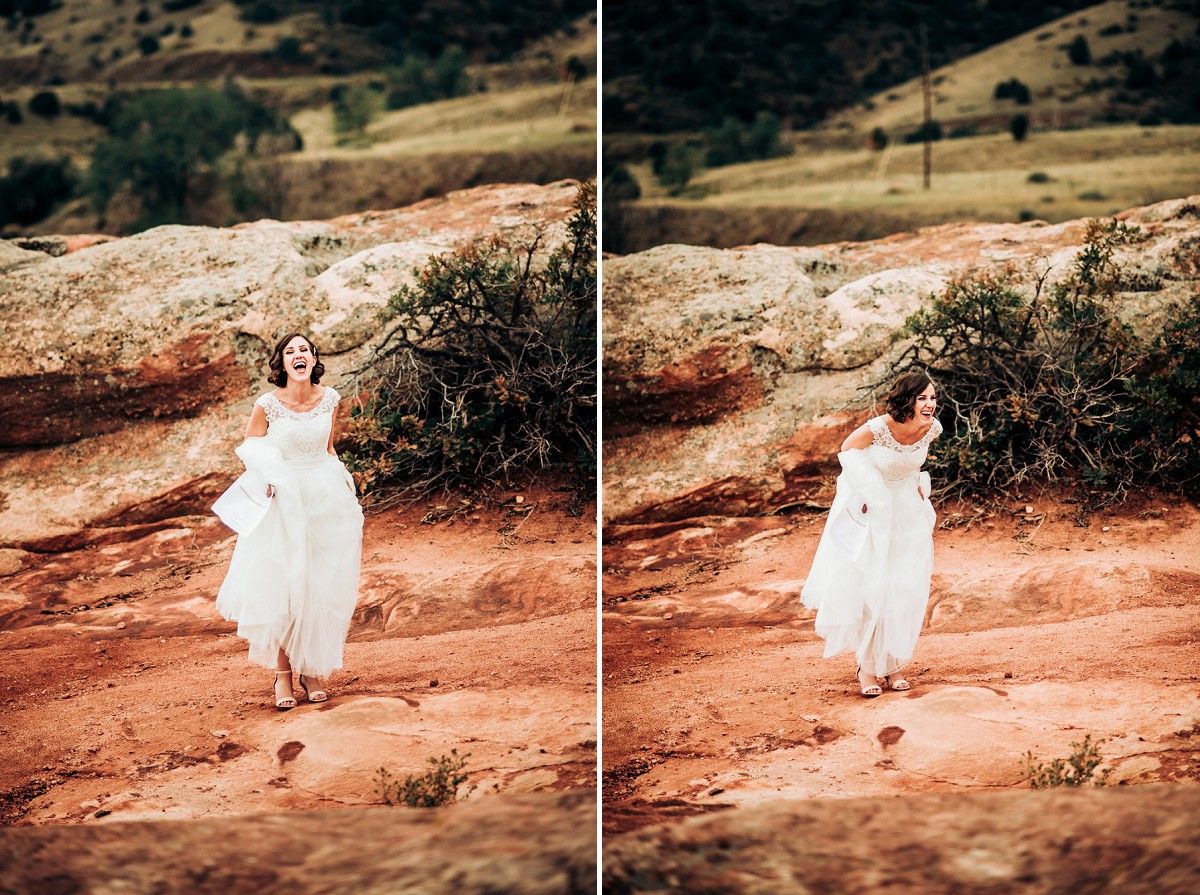 Bride in flowing white dress walking on red desert rocks during sunset photoshoot.