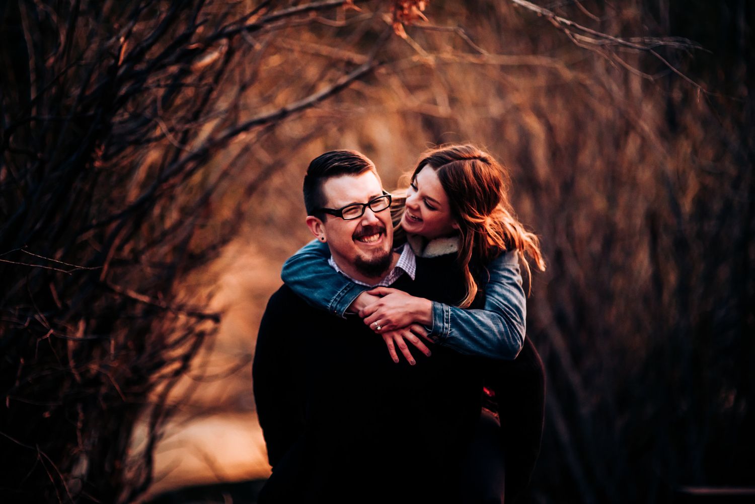 Couple sharing playful moment against warm sunset backdrop.