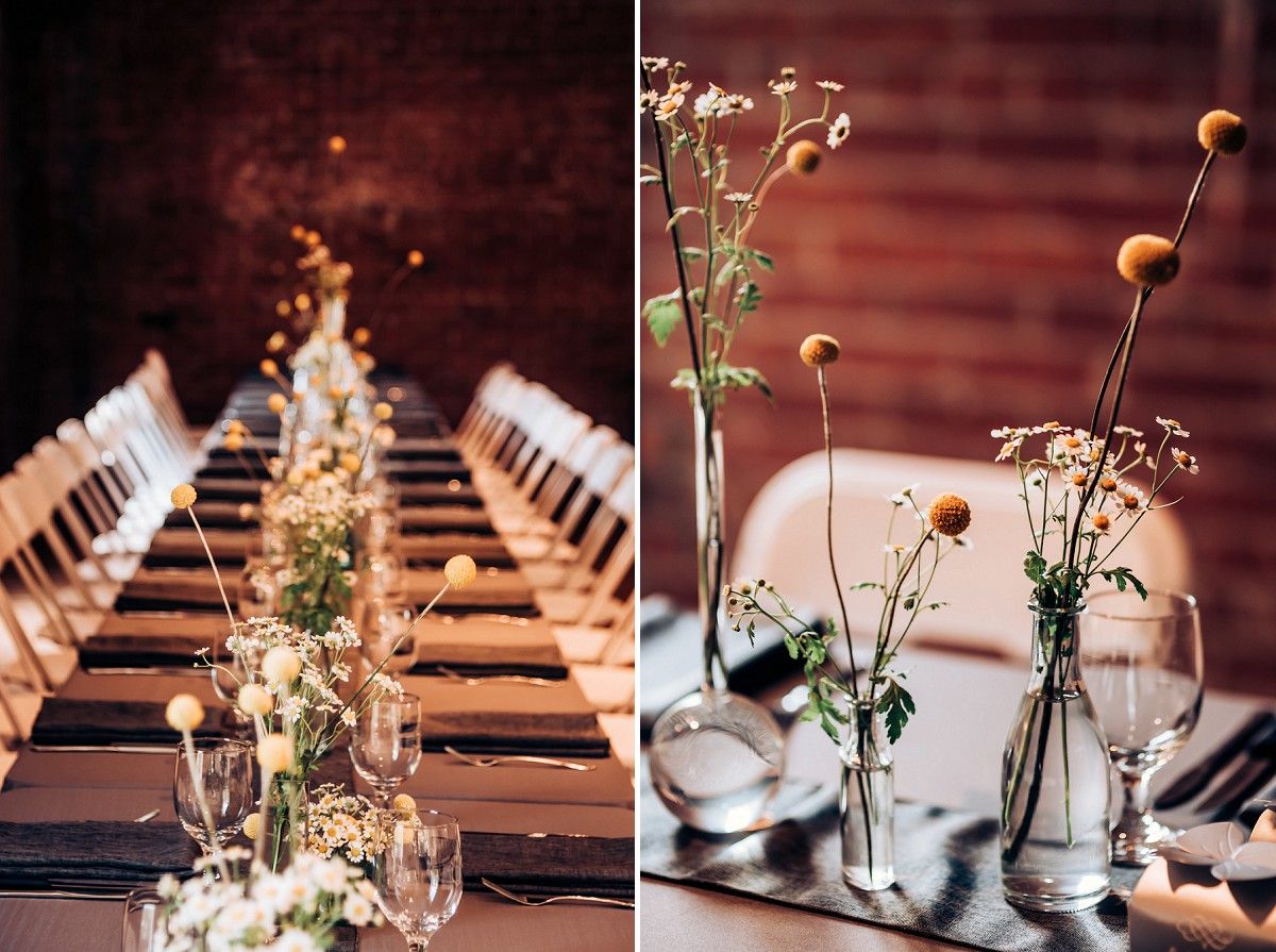 Long dining table set for wedding reception with delicate floral centerpieces and glowing ambiance.