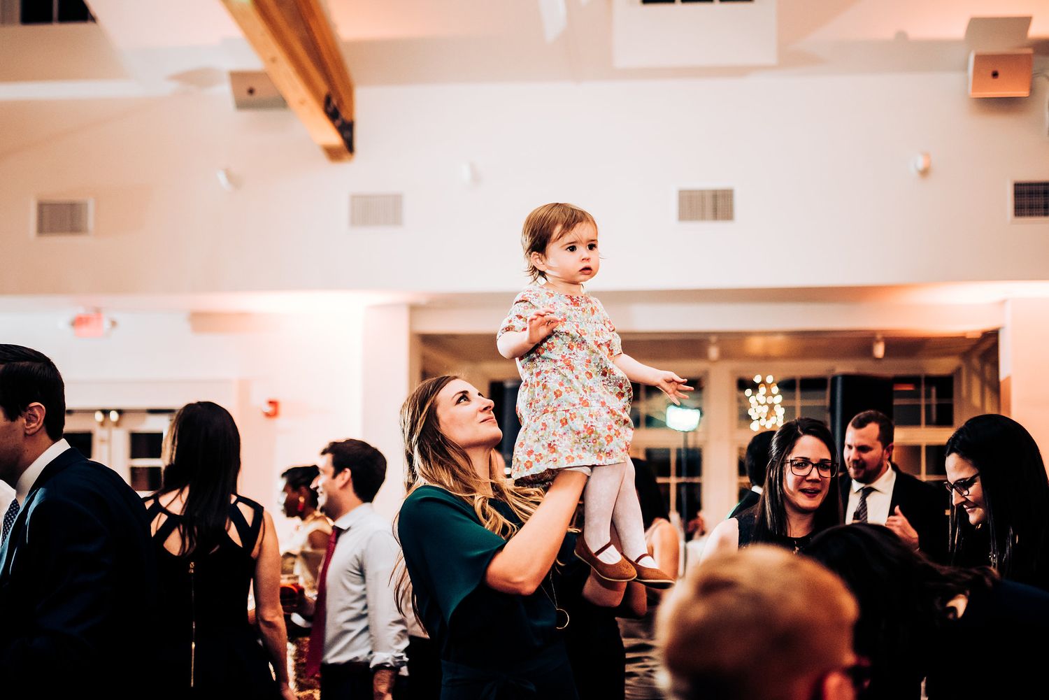 A toddler is lifted up during a lively wedding reception dance party.