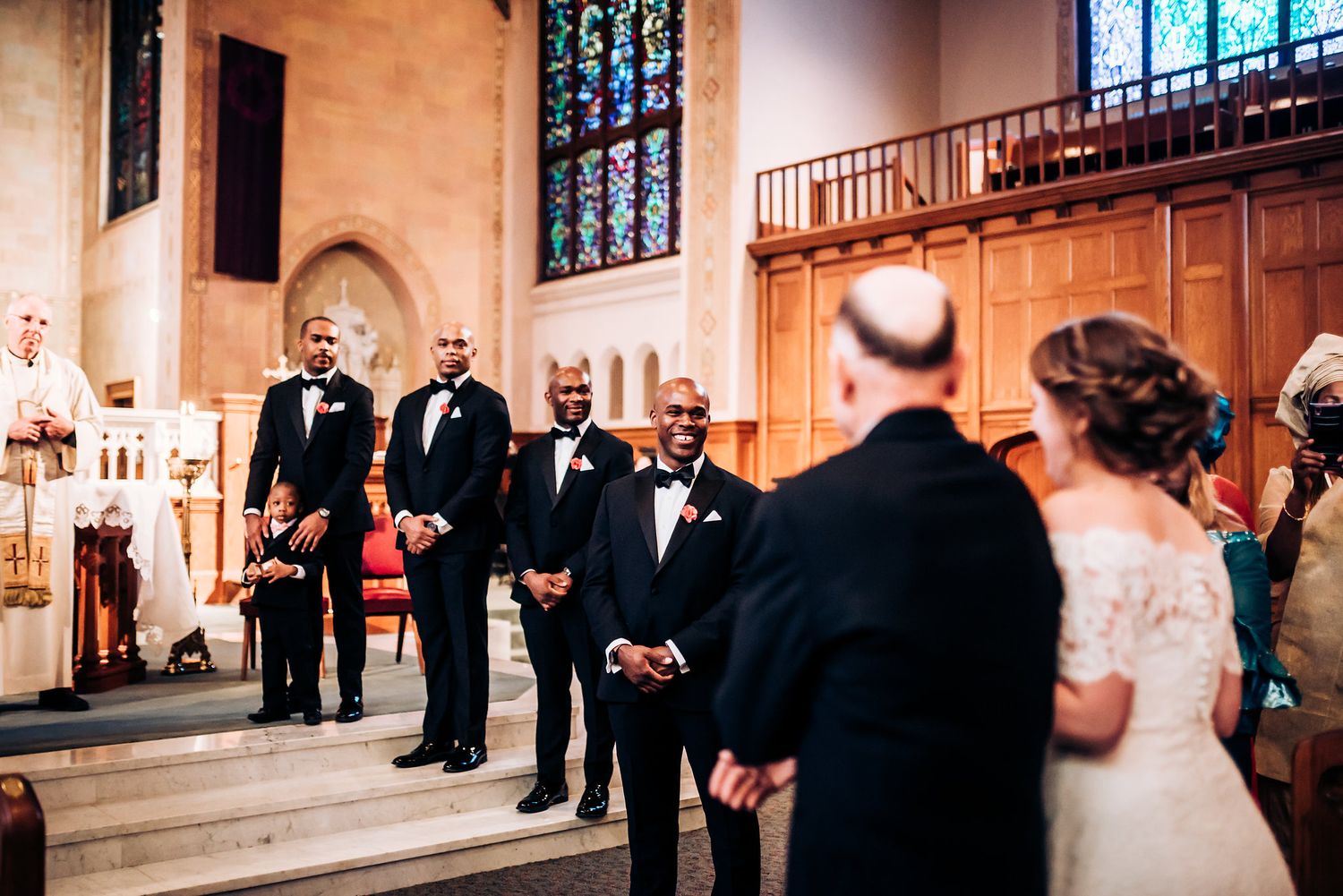 Wedding ceremony participants stand at the altar steps of a grand church.