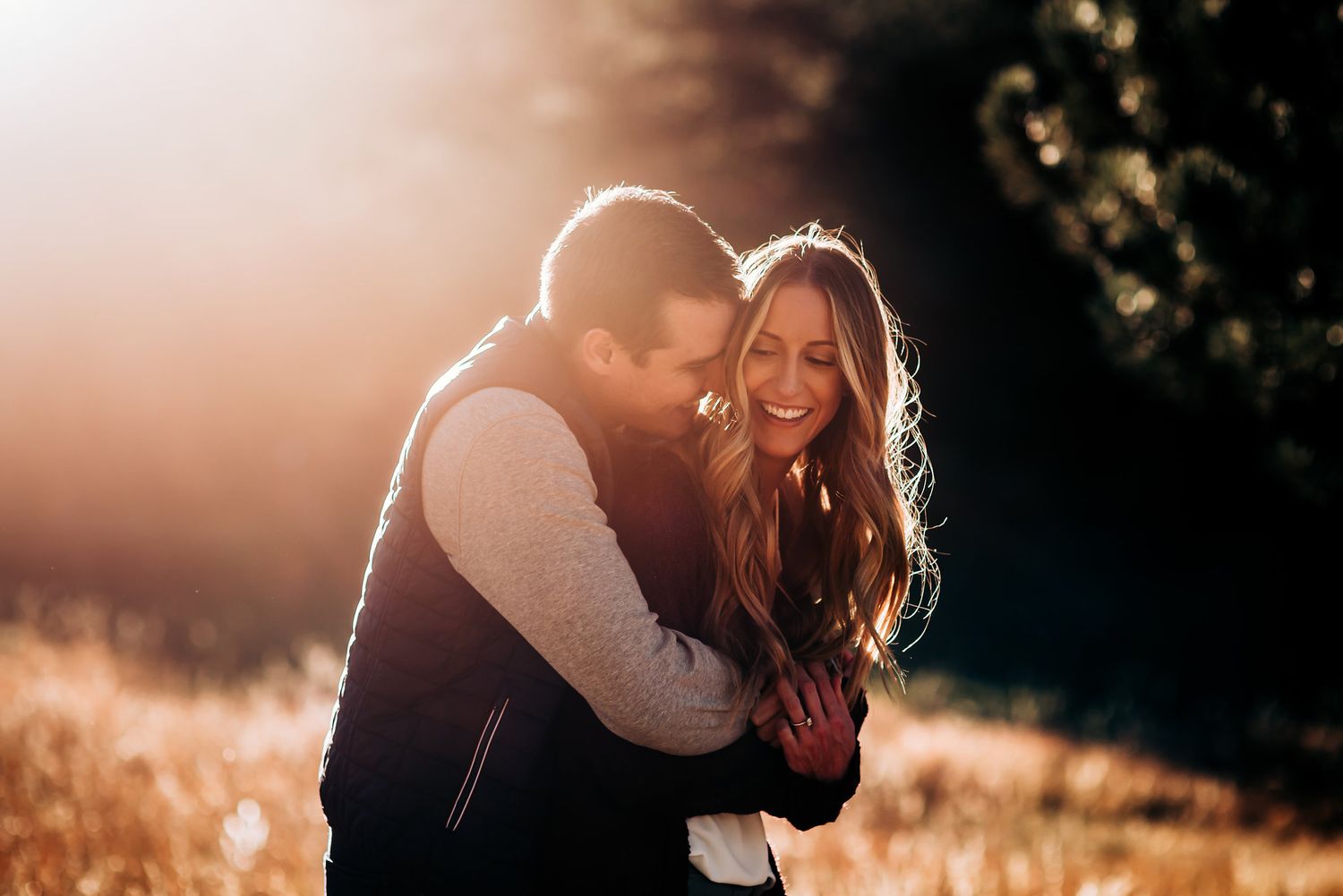 A tender embrace shared between two people during golden hour with sunlight creating a warm glow.