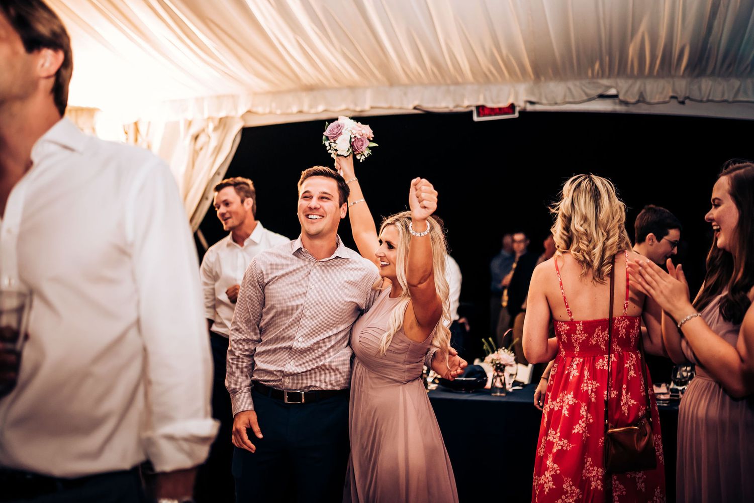 Party guests dance and celebrate at an elegant indoor wedding reception.
