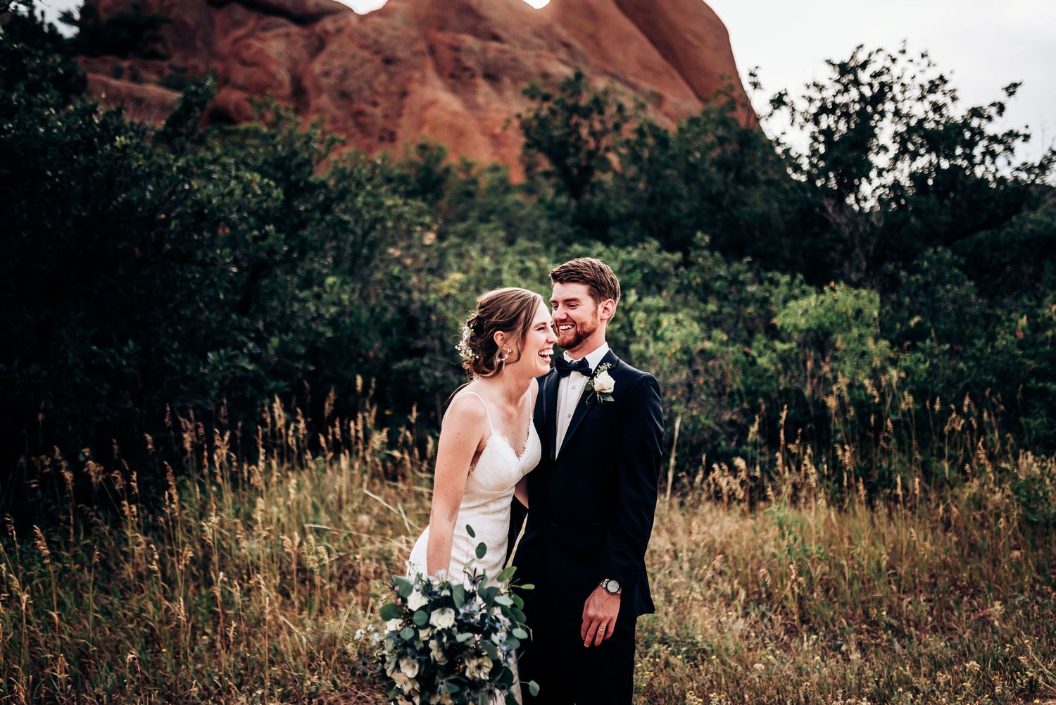 A couple shares an intimate moment against stunning red rock formations and natural landscape.
