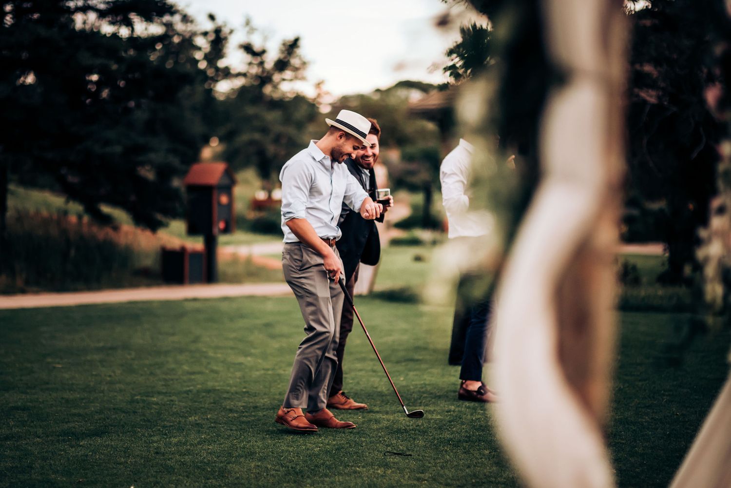 Golfer taking a swing on lush green course with mountain scenery in background.
