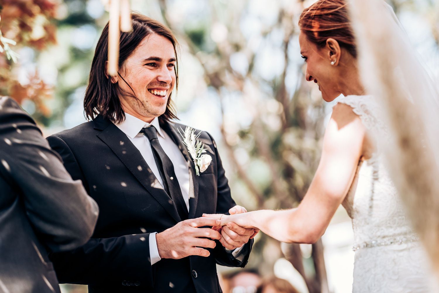 Wedding couple exchanging rings during outdoor ceremony with natural lighting.