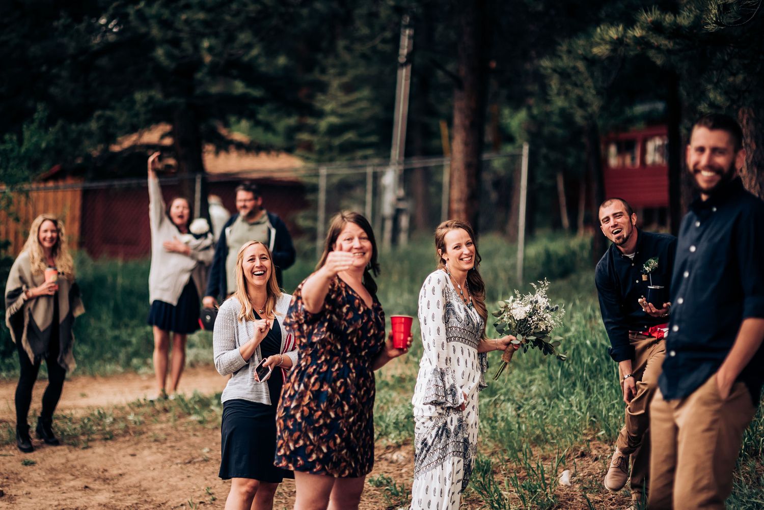 Group celebrating outdoors on a sunny day with natural scenery in background.
