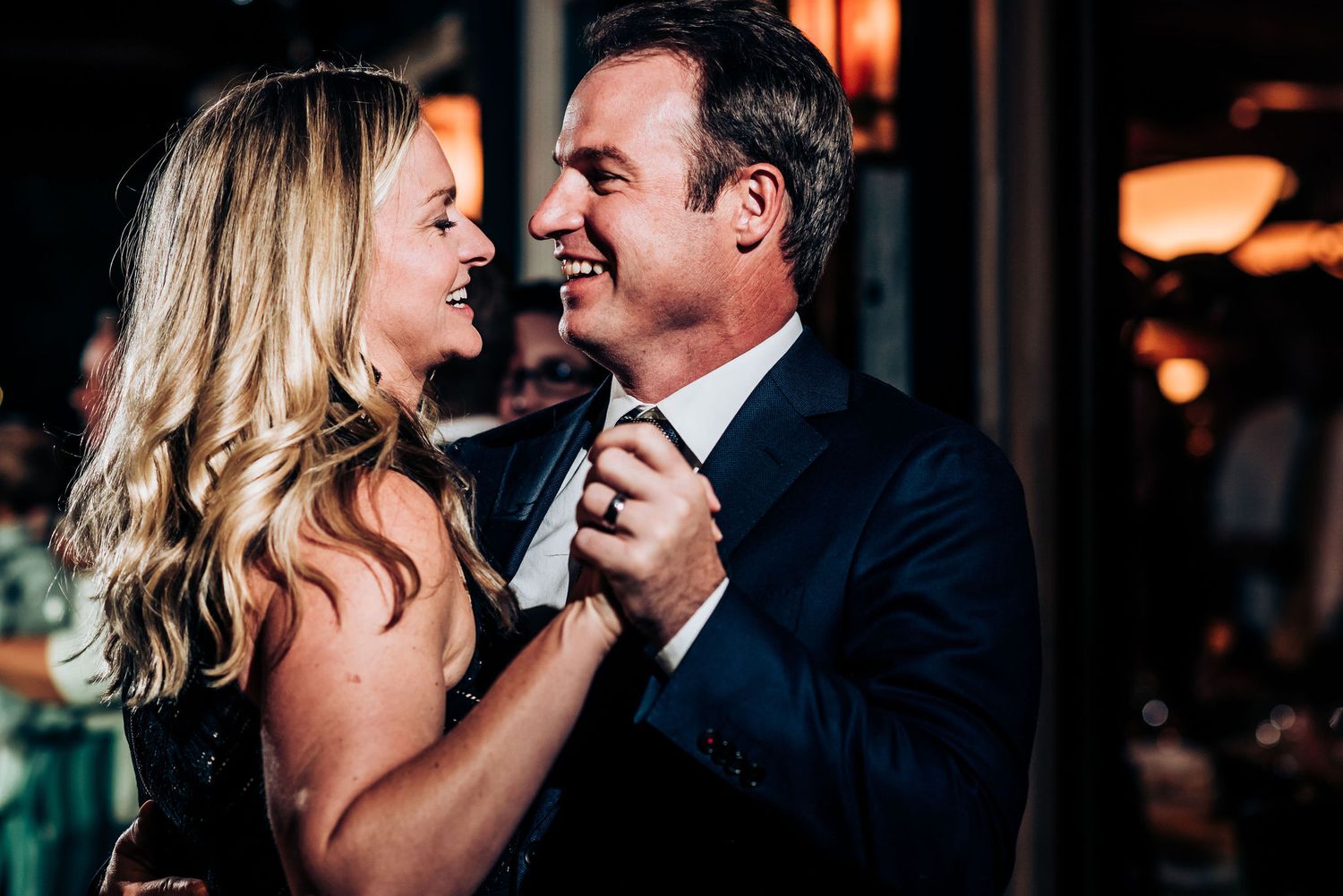A couple shares an intimate dance moment under ambient lighting at an evening event.