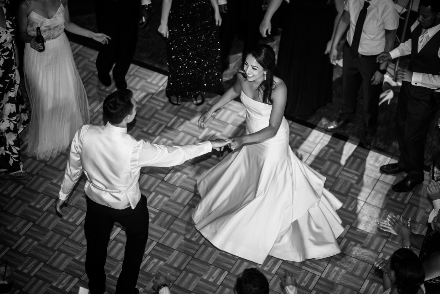 Couples dancing on a parquet floor during an energetic wedding reception.