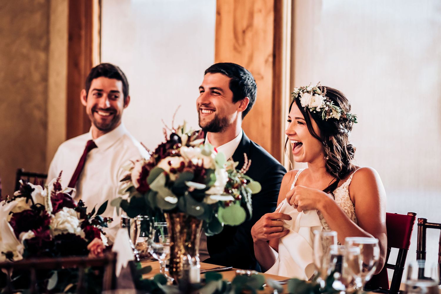 Joyful celebration at wedding reception with floral centerpieces and elegant table settings.