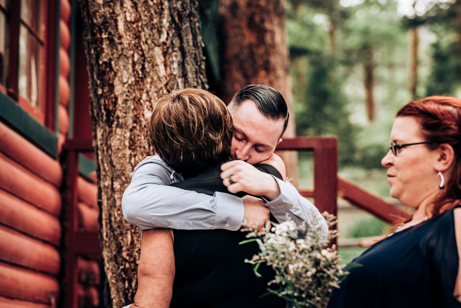 Intimate moment of embrace during a celebration outside a rustic cabin.