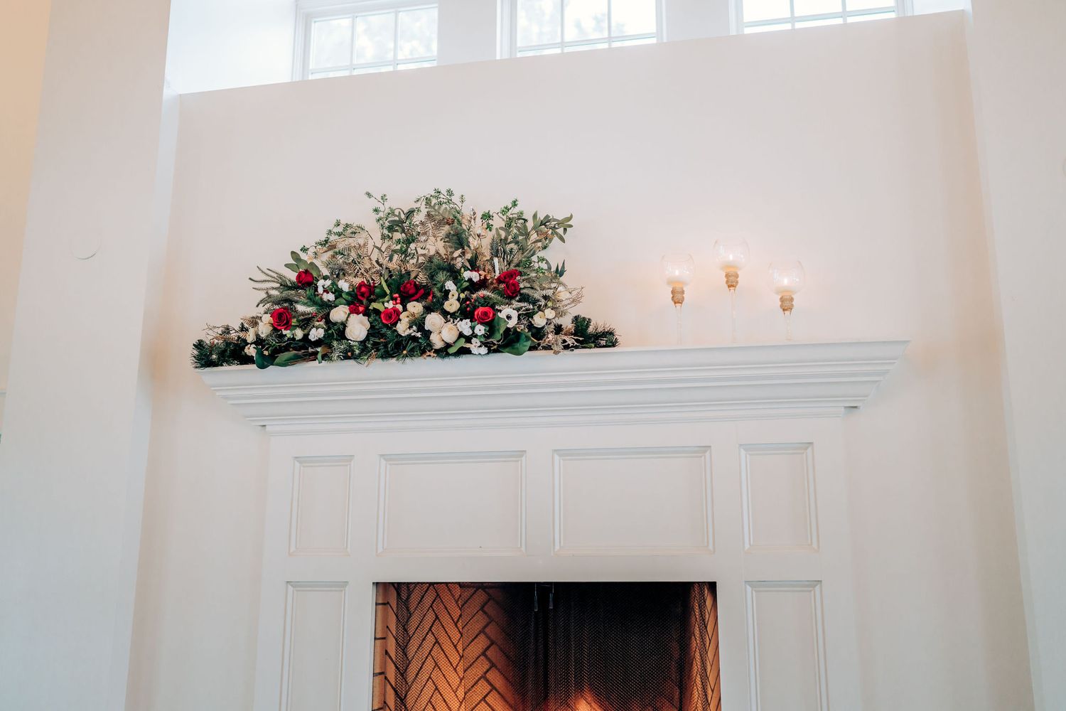 Close-up of white fireplace mantel decorated with pink and white floral arrangement.