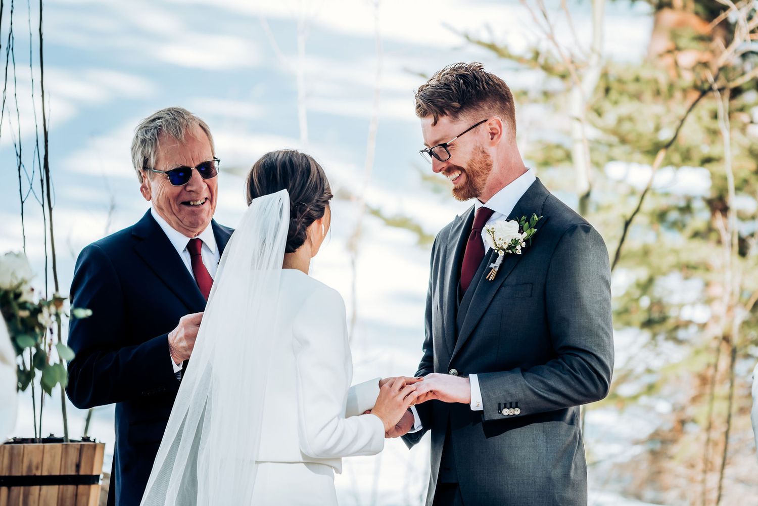 Ring exchange during sunny winter wedding ceremony outdoors.
