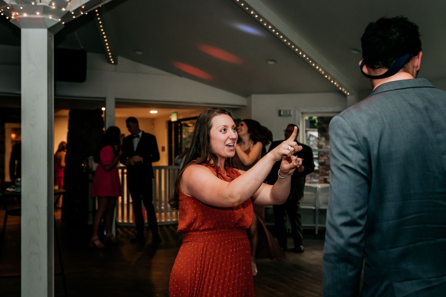 Guest dances enthusiastically in red dress at indoor reception.