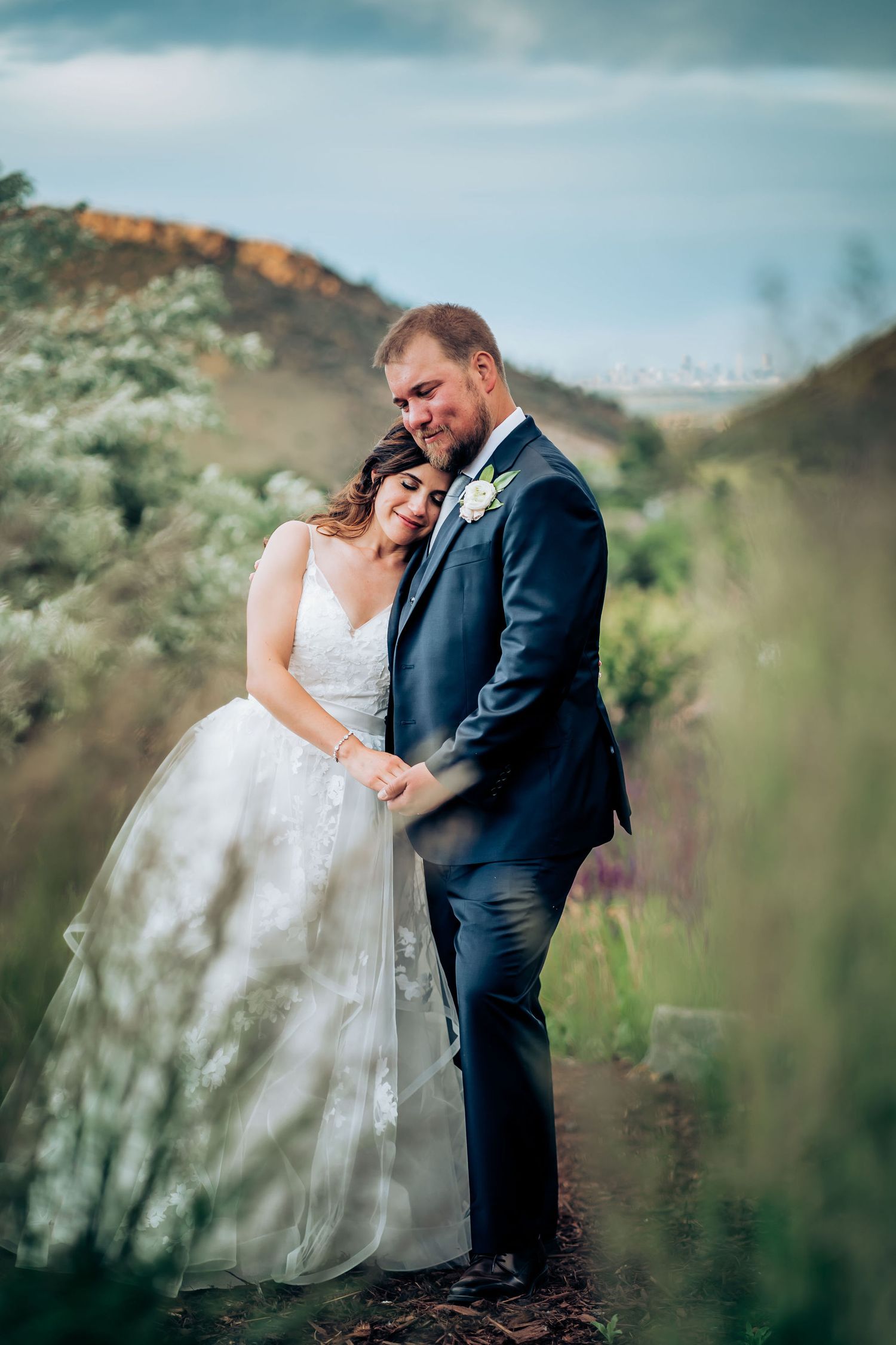 An intimate wedding portrait captured among wild grasses on a hillside.