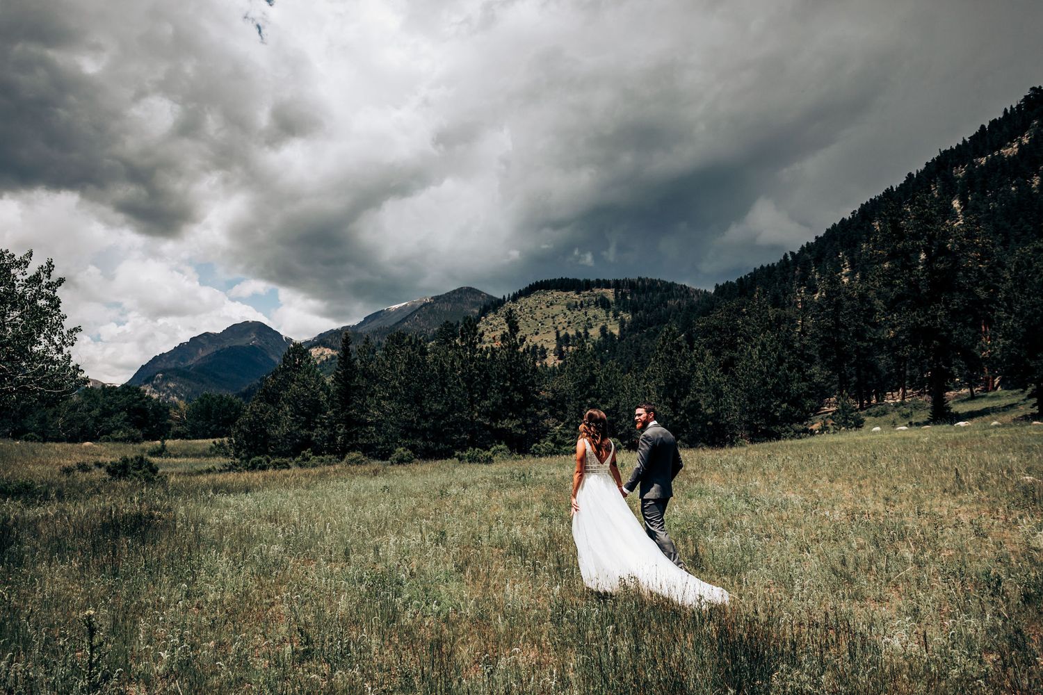 A dramatic mountain wedding photo with stormy clouds and peaks in the background.