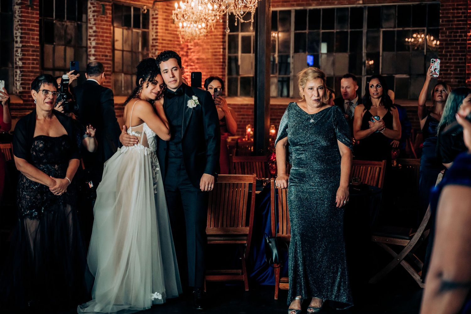 Wedding reception entertainment in a rustic venue with exposed brick and chandeliers.