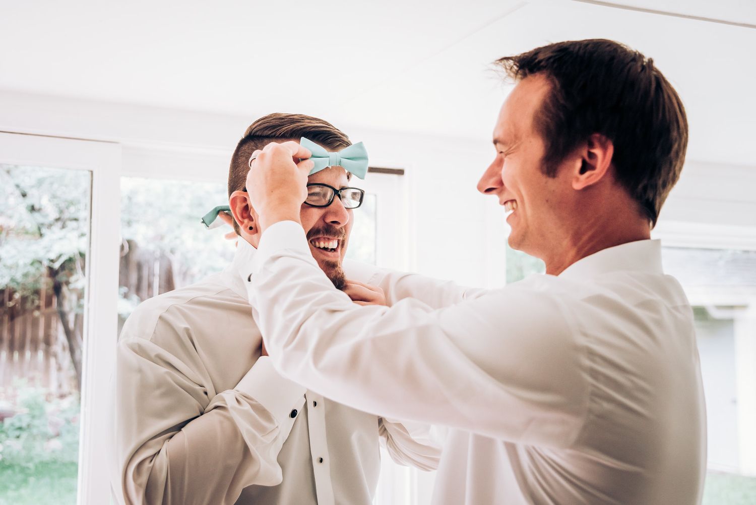 Groomsmen laughing and adjusting ties before ceremony.