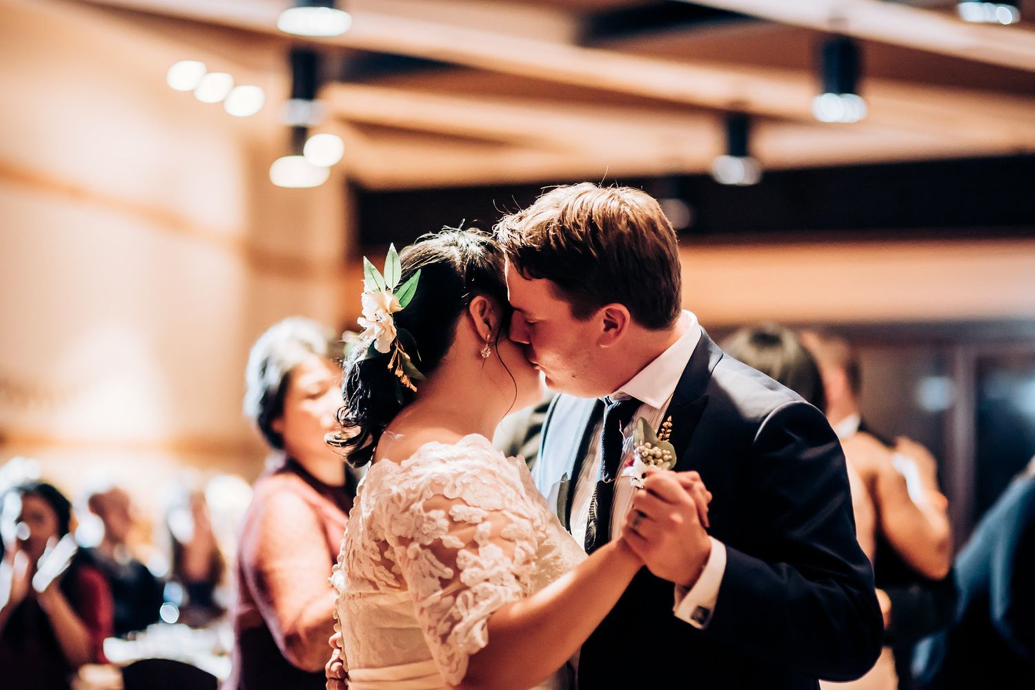 Close-up shot of an intimate dance between a bride in lace and groom in tuxedo.