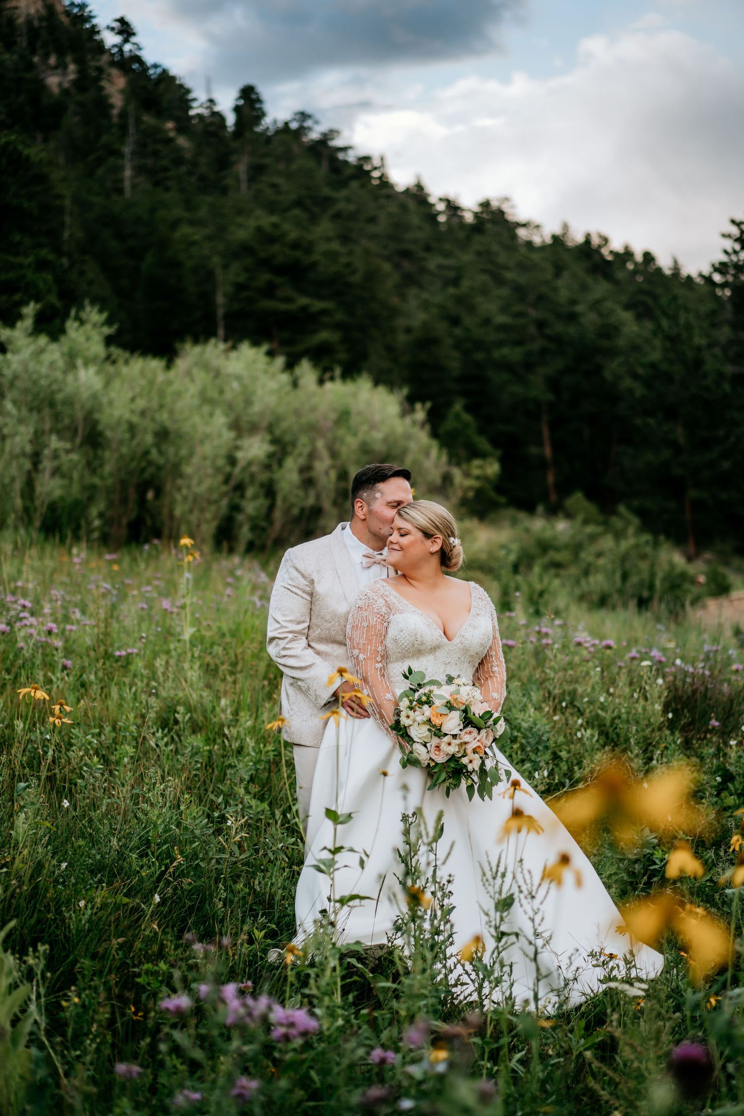 Newlyweds share an intimate moment in a mountain meadow filled with summer wildflowers.