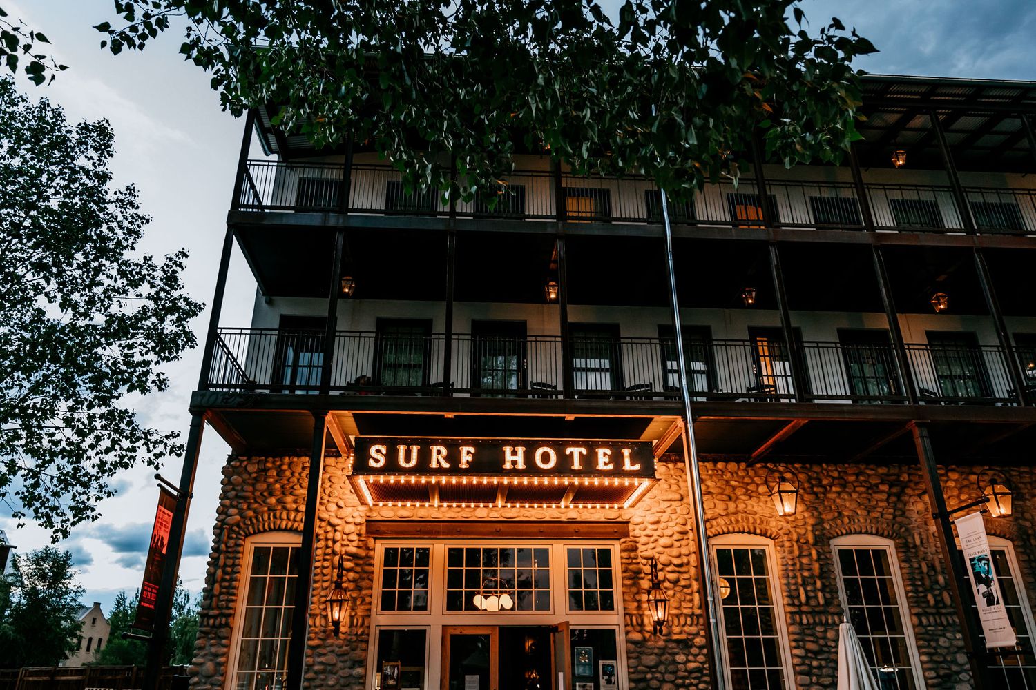 Illuminated Surf Hotel building exterior at dusk with warm glowing signage.