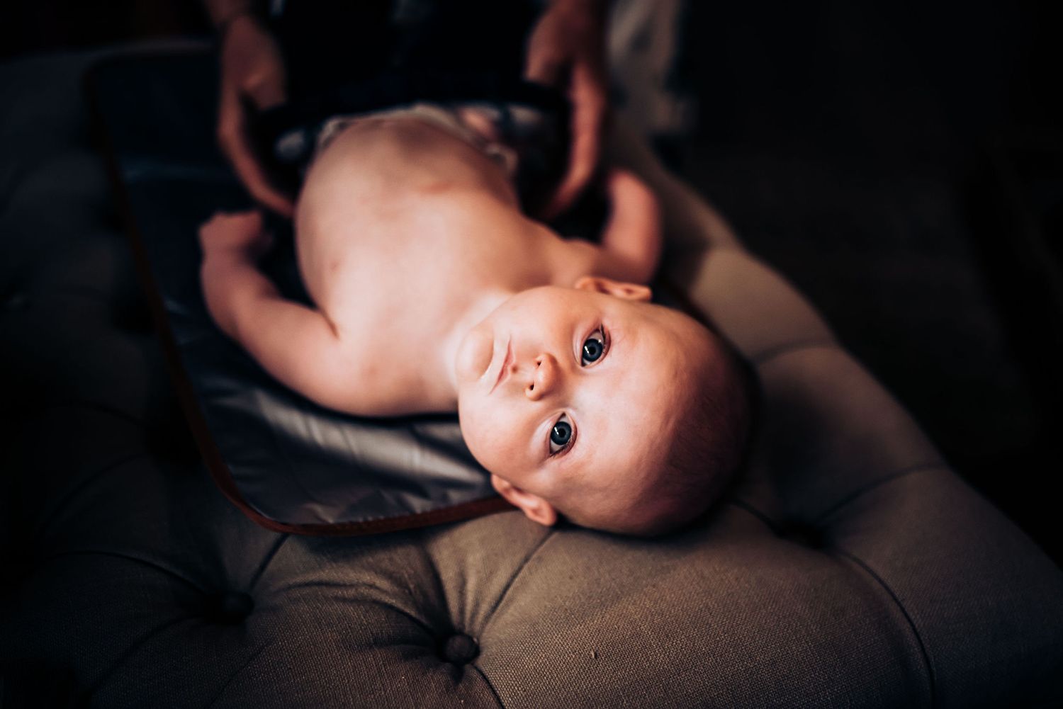 Baby lying on dark fabric in intimate portrait setting.