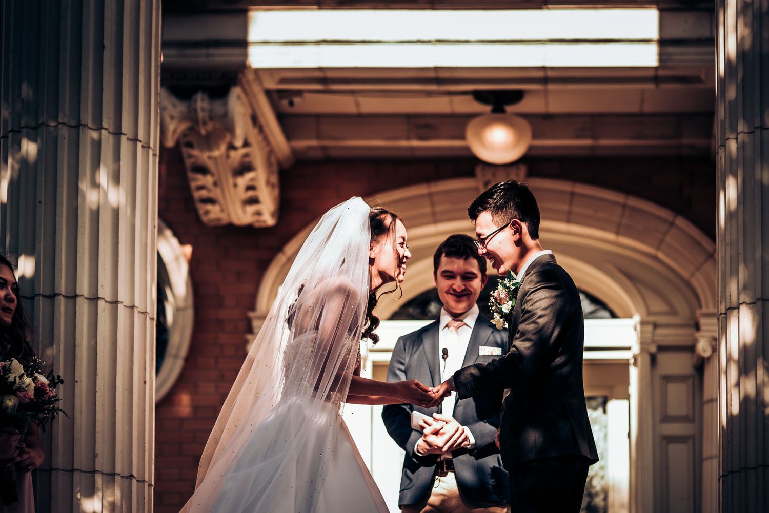 Intimate wedding ceremony moment captured between stone columns.