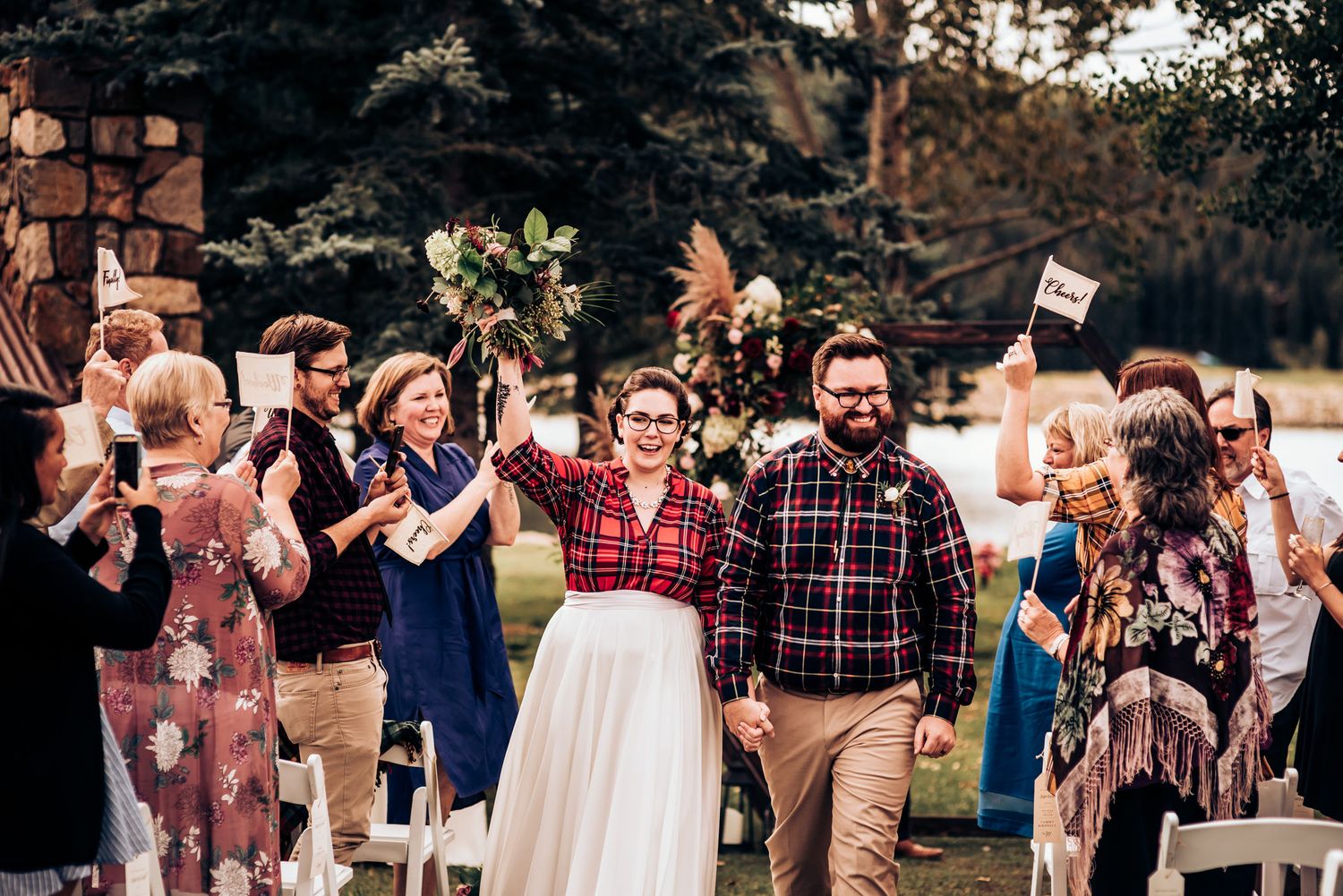 Wedding celebration on a lawn with guests cheering and celebrating in a festive atmosphere.