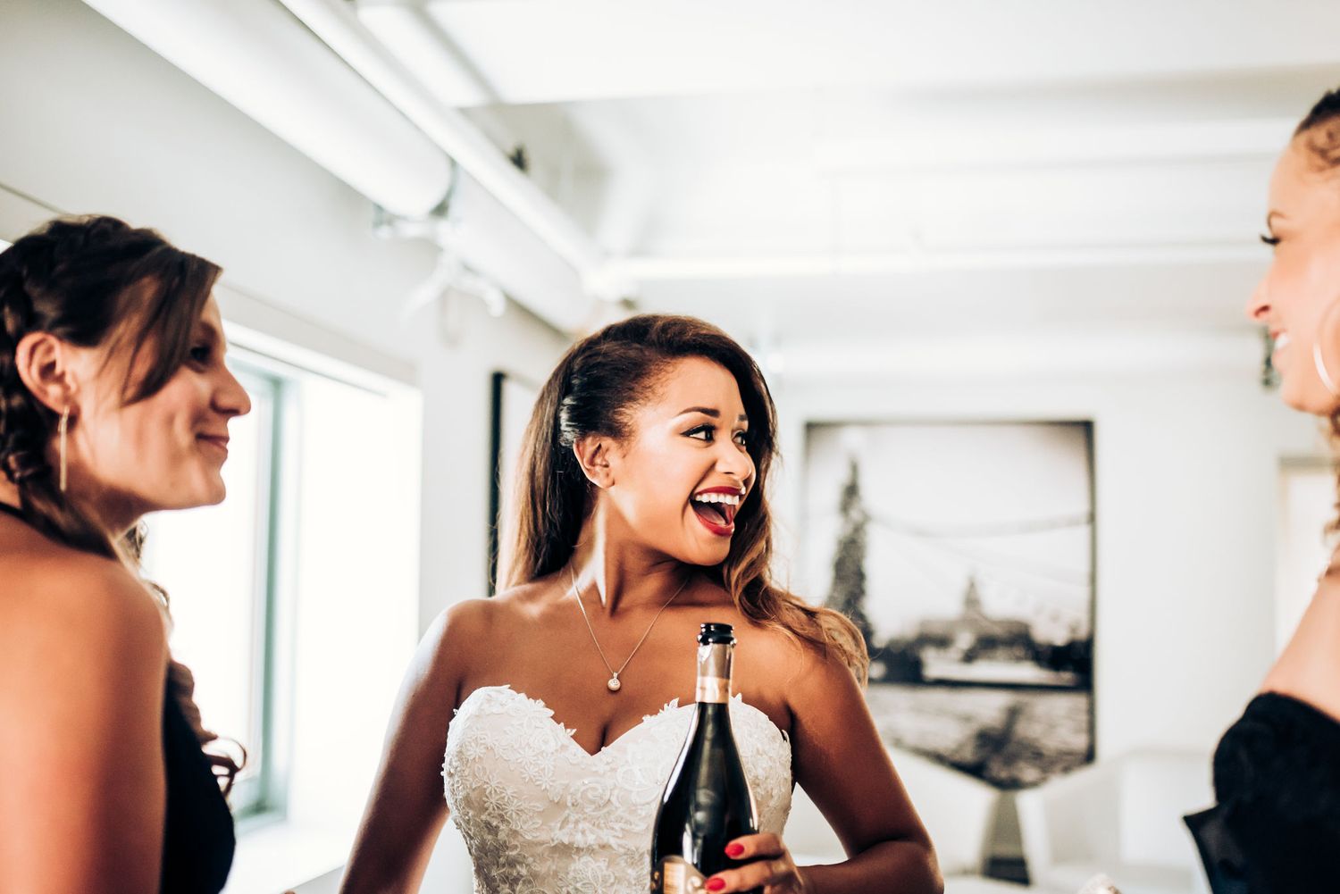 Wedding party shares champagne and laughter during bridal preparations.