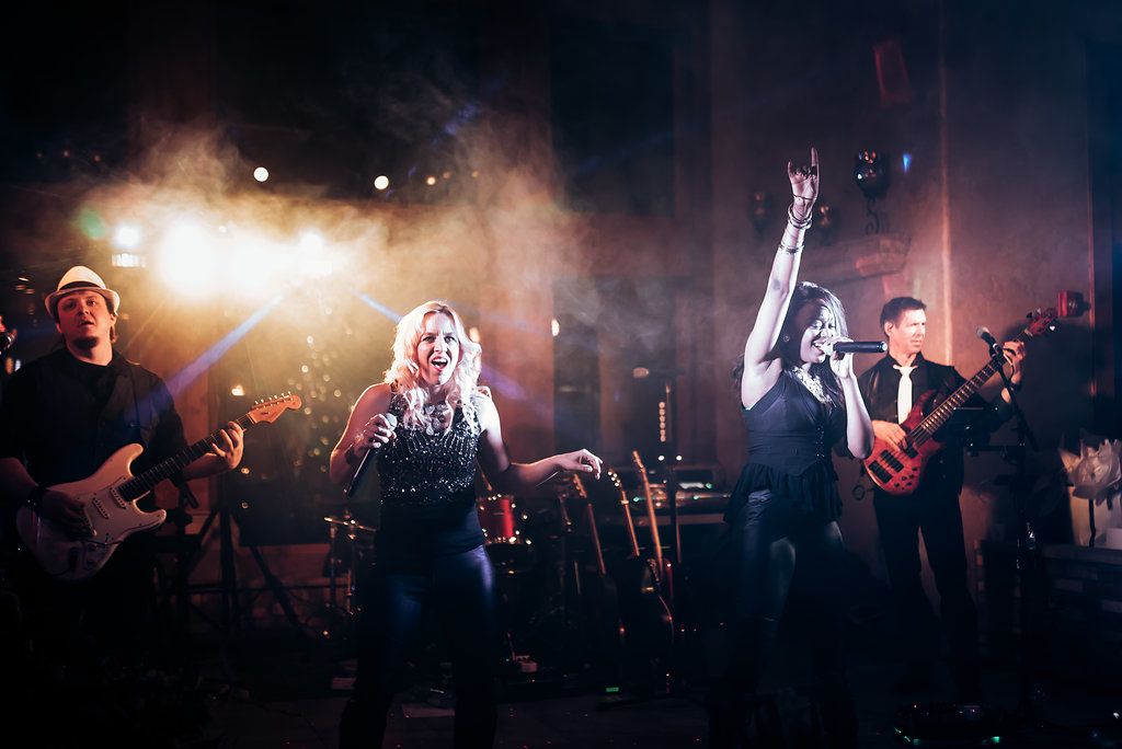 Energetic live band performance with dramatic stage lighting at wedding reception.