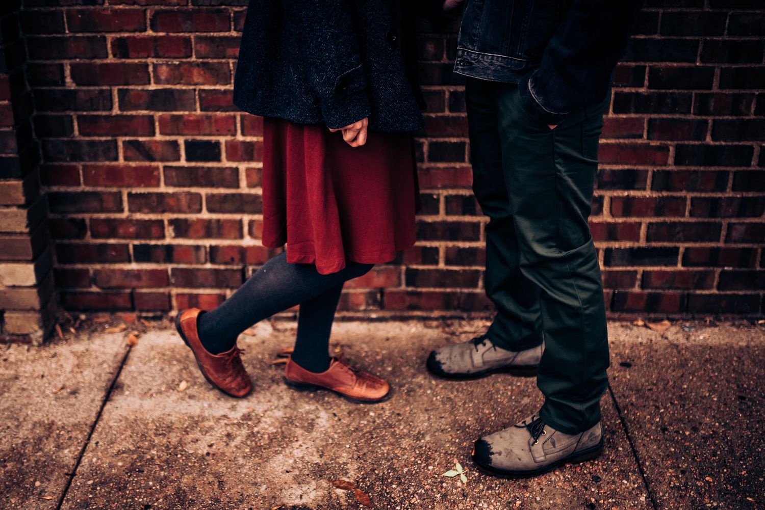 Close up of two pairs of boots against red brick wall background.