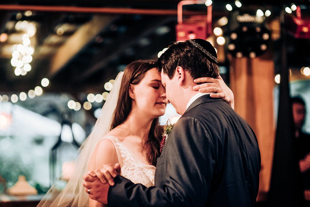 A romantic moment between a couple dancing at their wedding reception under twinkling lights.