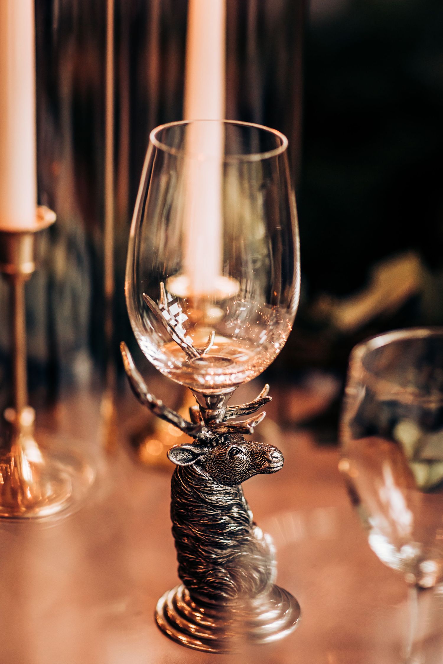 Elegant wine glass with decorative stag base captured in warm candlelight.