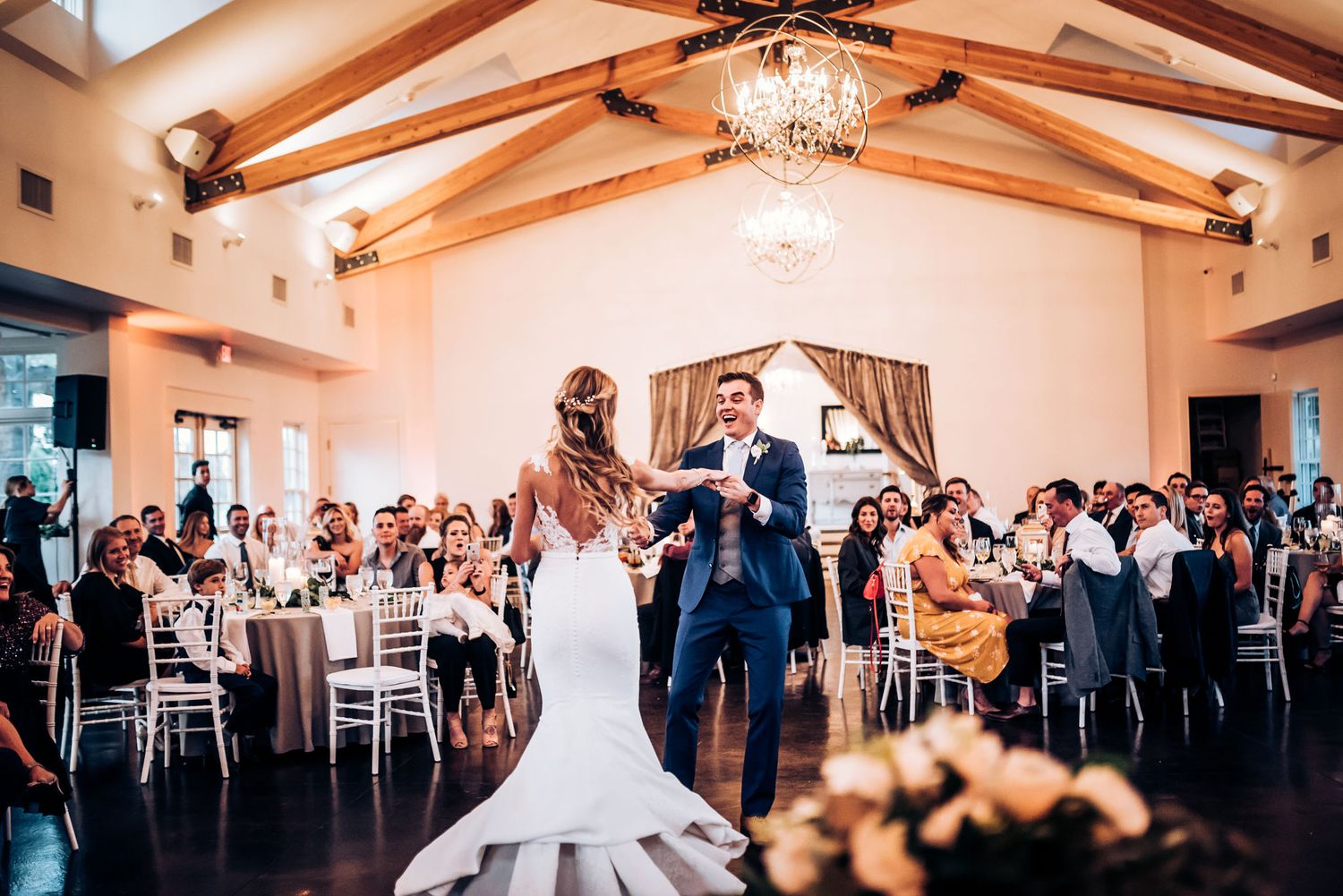 A couple performs their first dance in an elegant ballroom with vaulted ceilings.