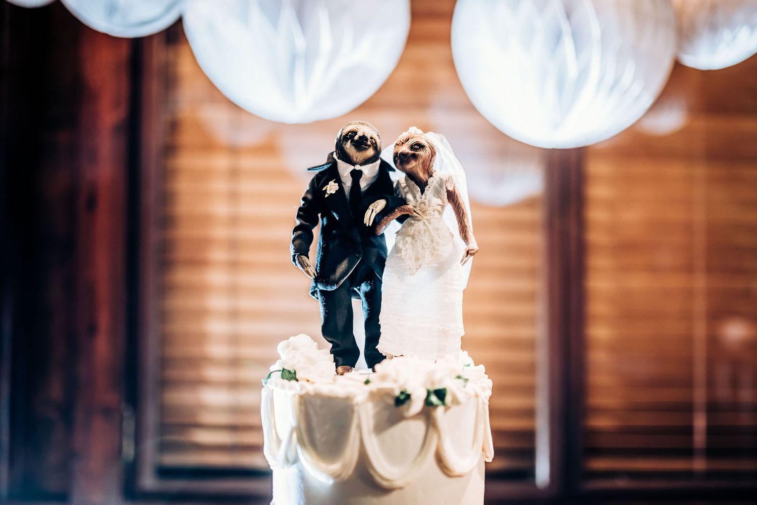 Classic bride and groom cake topper on white wedding cake with delicate details.