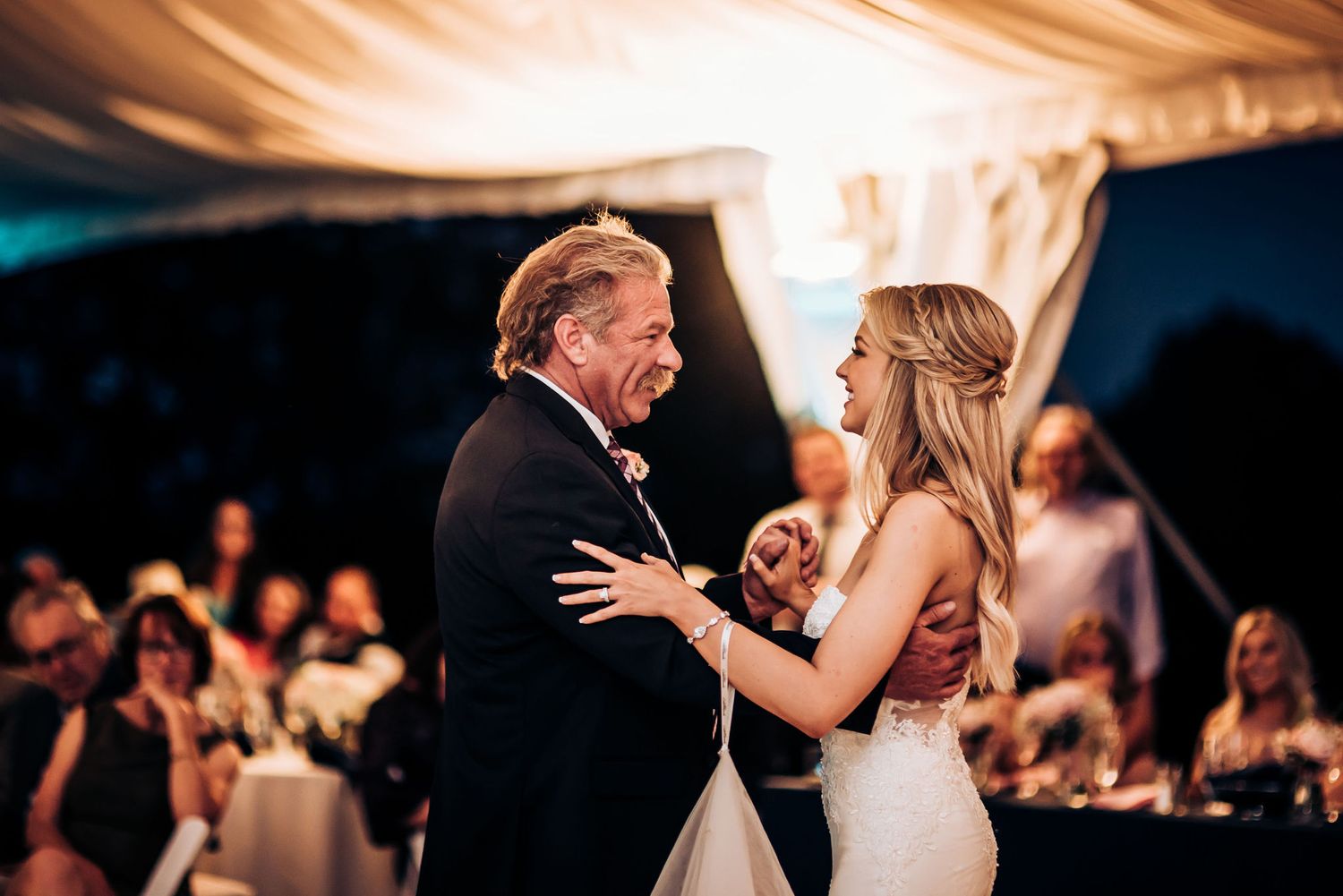 A tender moment during a special dance at an evening wedding reception under warm lighting.