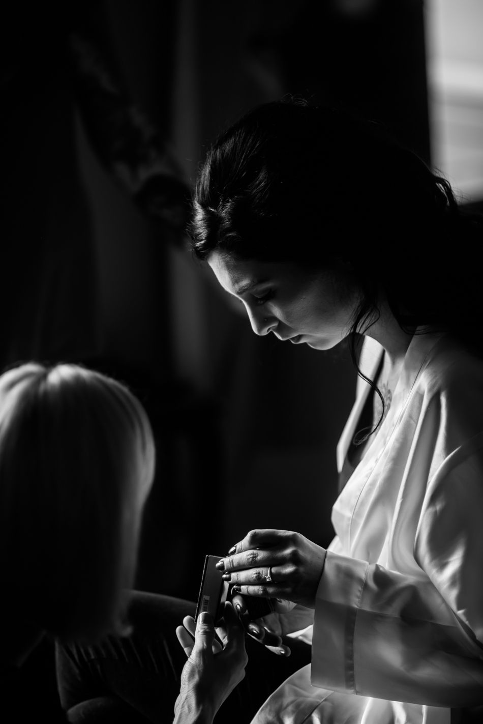 Black and white portrait of someone in white robe during wedding preparation.