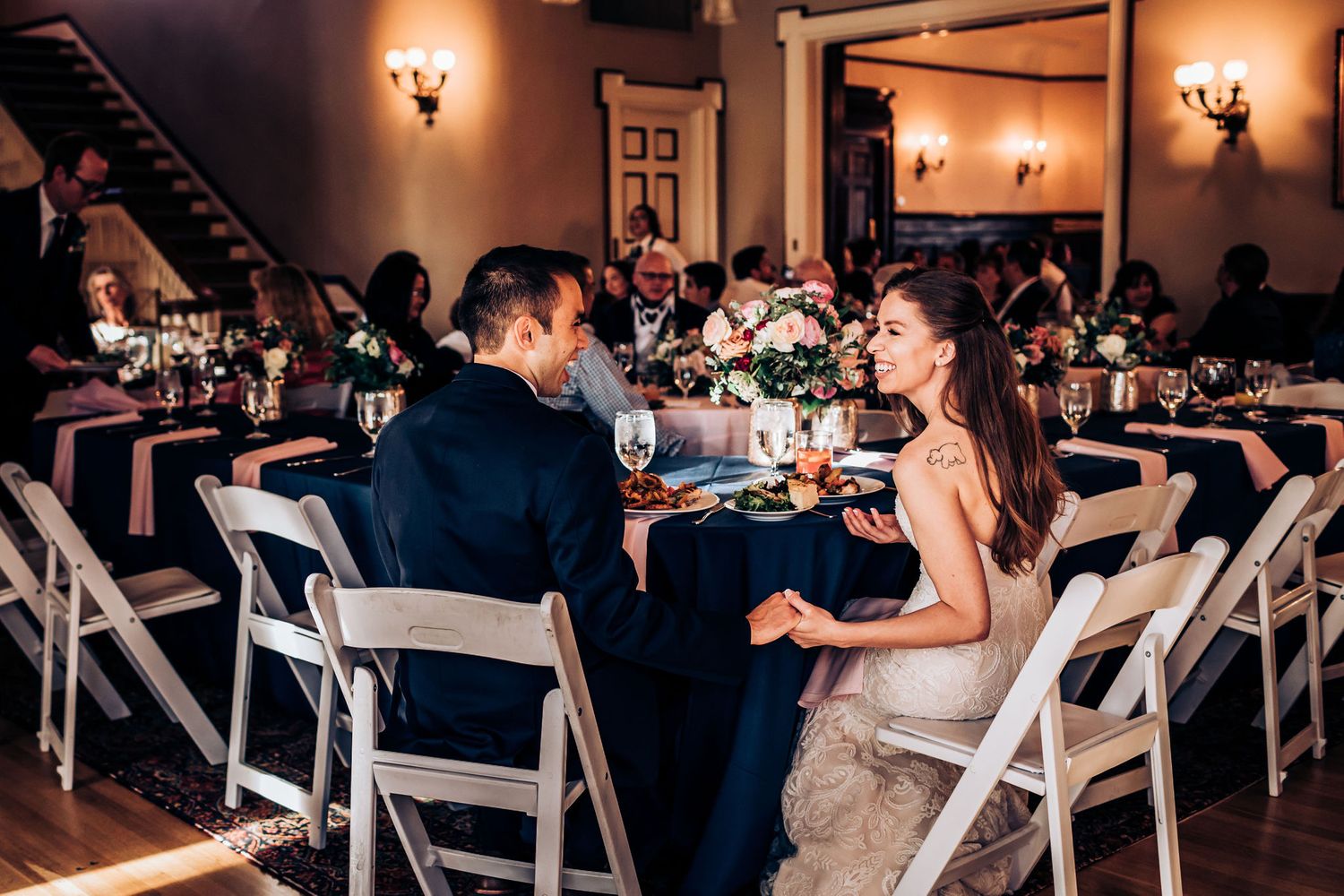 Guests seated at reception dining tables with elegant lighting and decor.