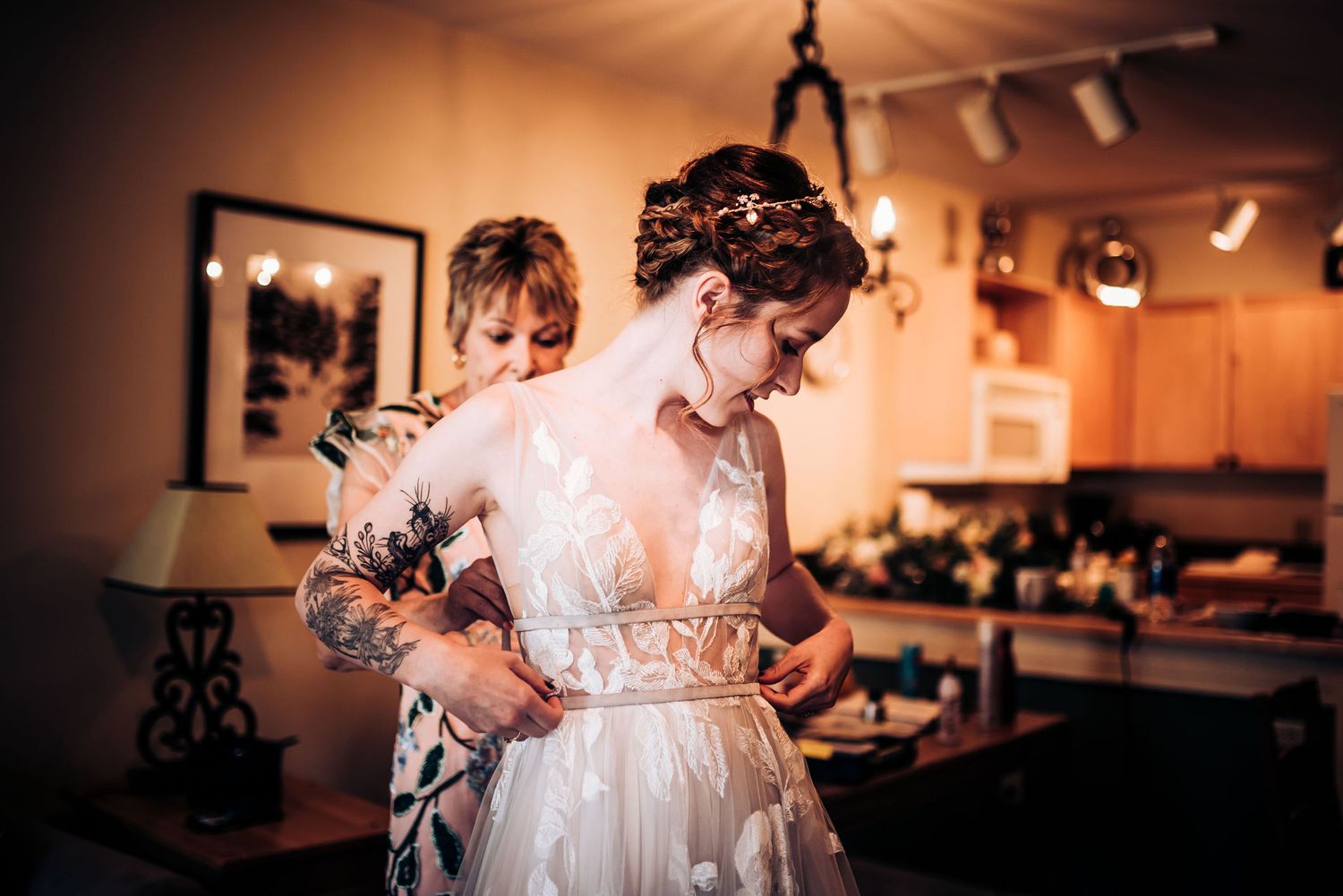 Candid moment of wedding dress preparations in warmly lit room.