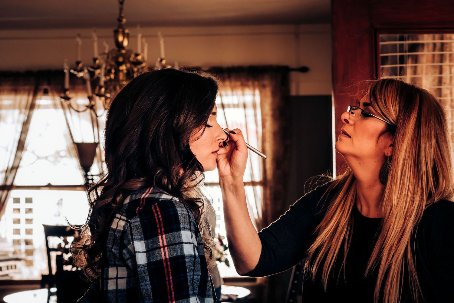 A makeup application session taking place in a room with warm lighting and vintage decor.