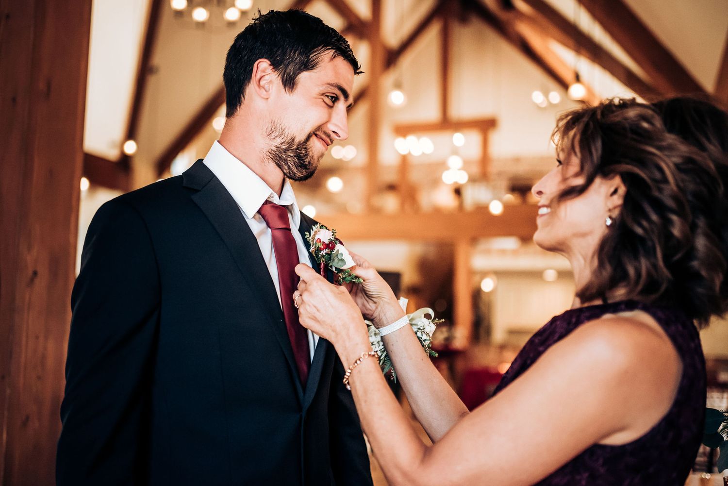A touching moment during wedding preparations as someone adjusts a boutonniere.