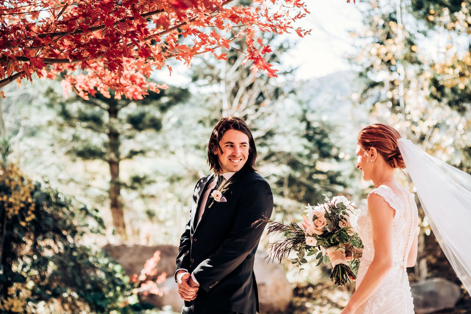 Wedding couple sharing a moment under bright red fall foliage.