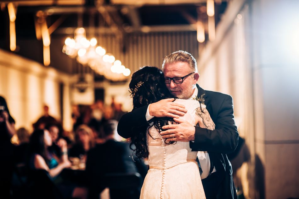 An intimate dance moment captured at an indoor wedding celebration with guests watching.