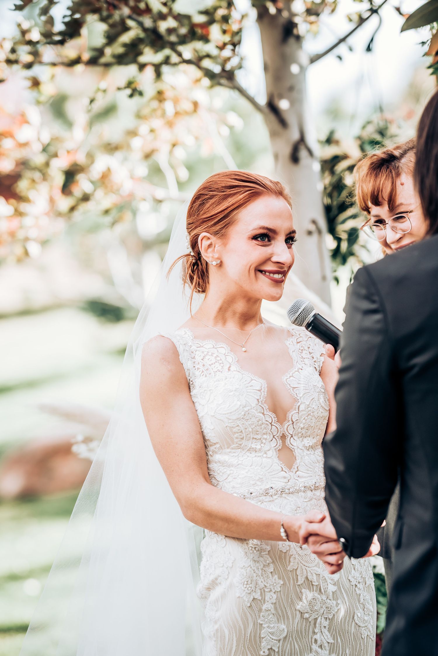 Outdoor wedding ceremony with beautiful lace dress and natural garden backdrop.