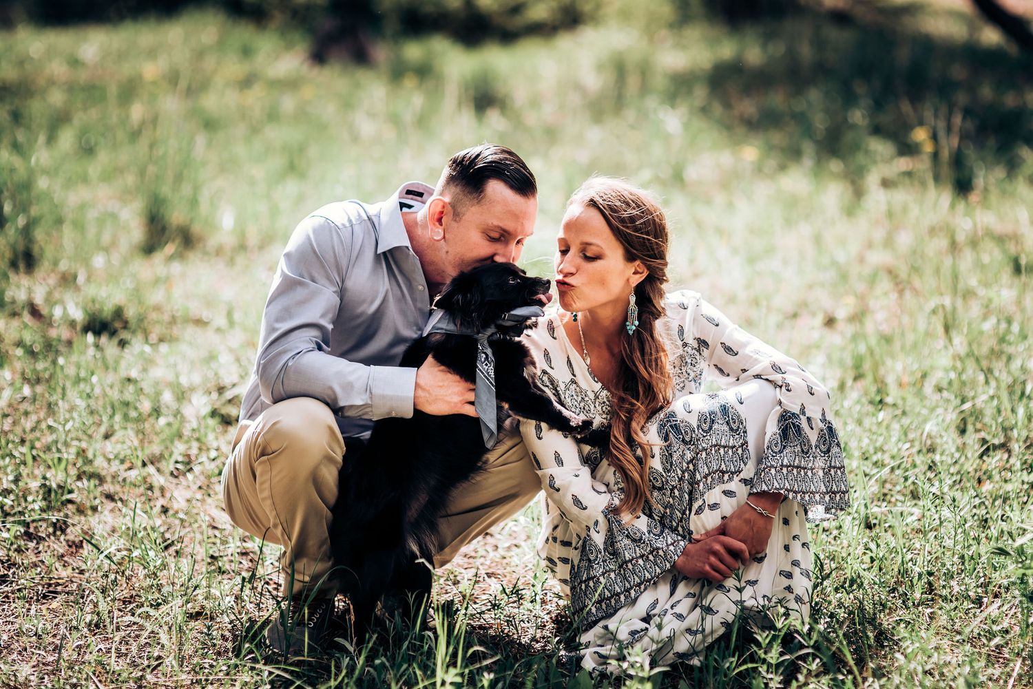 Two people sharing a candid laughing moment while sitting in a grassy meadow.