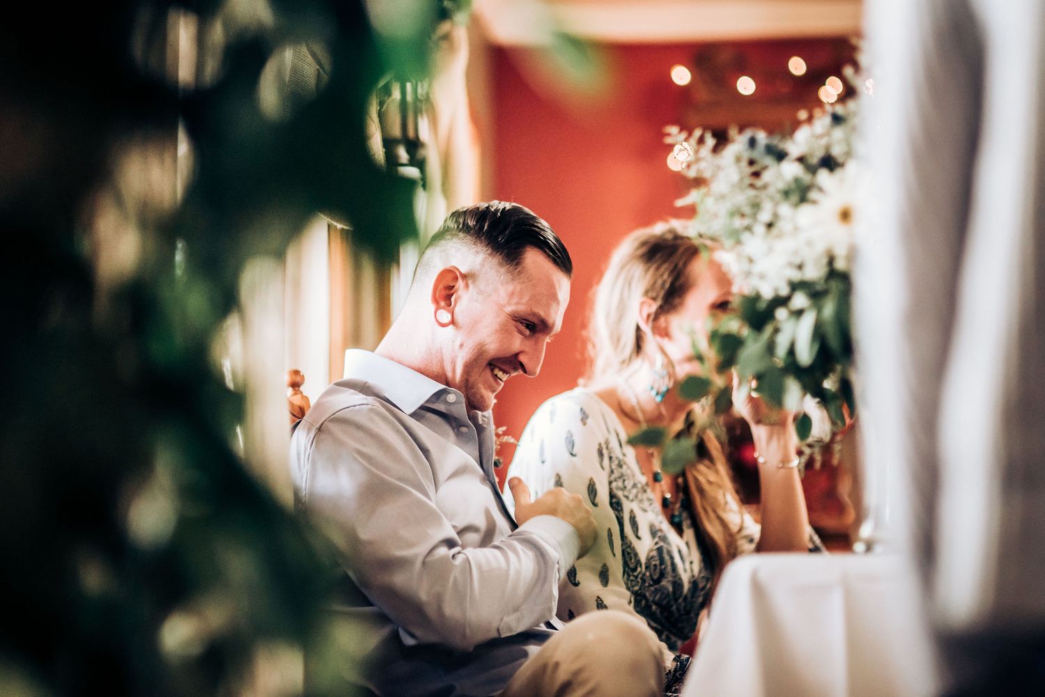 Wedding guests enjoying candid moments at an intimate reception under warm lighting and floral decorations.