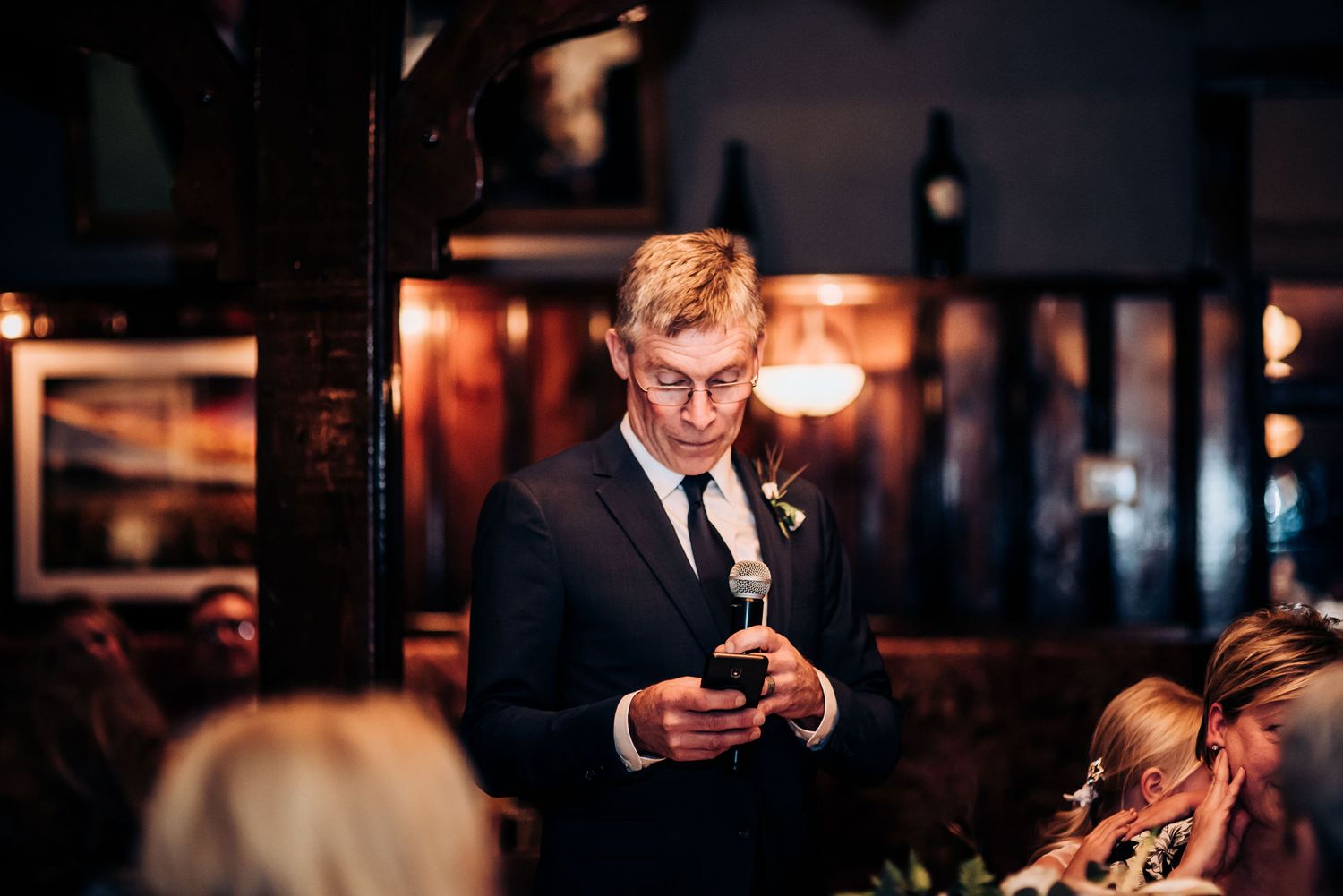 A formal guest checks their phone during an evening reception.