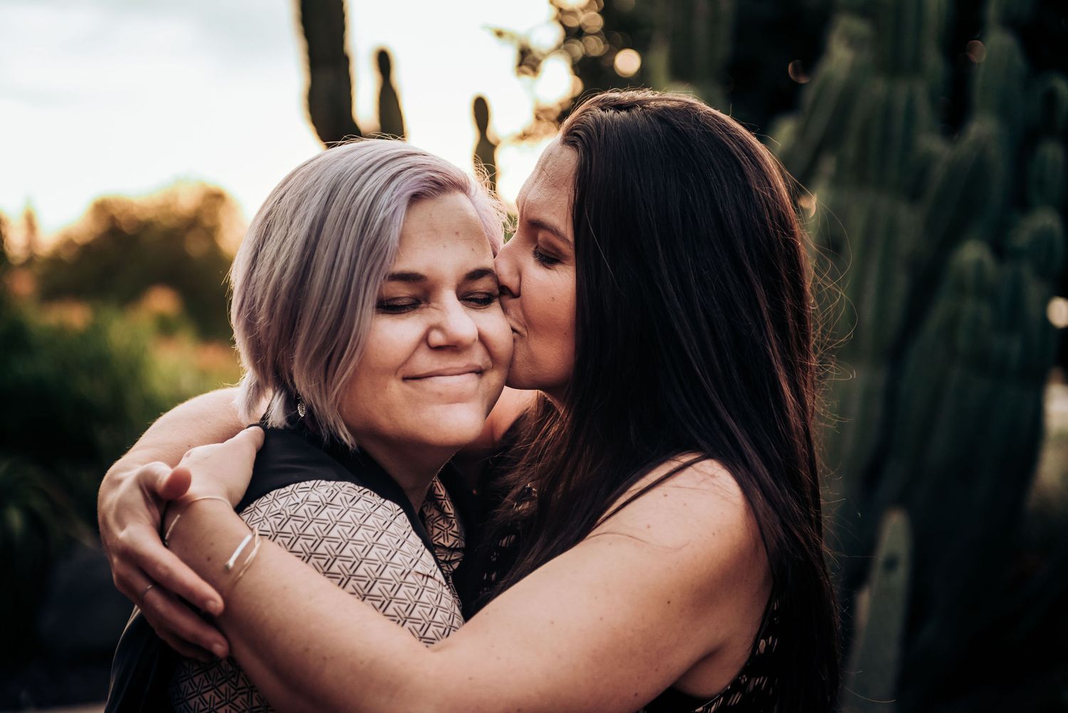 A loving couple sharing an intimate moment in a garden filled with desert plants.