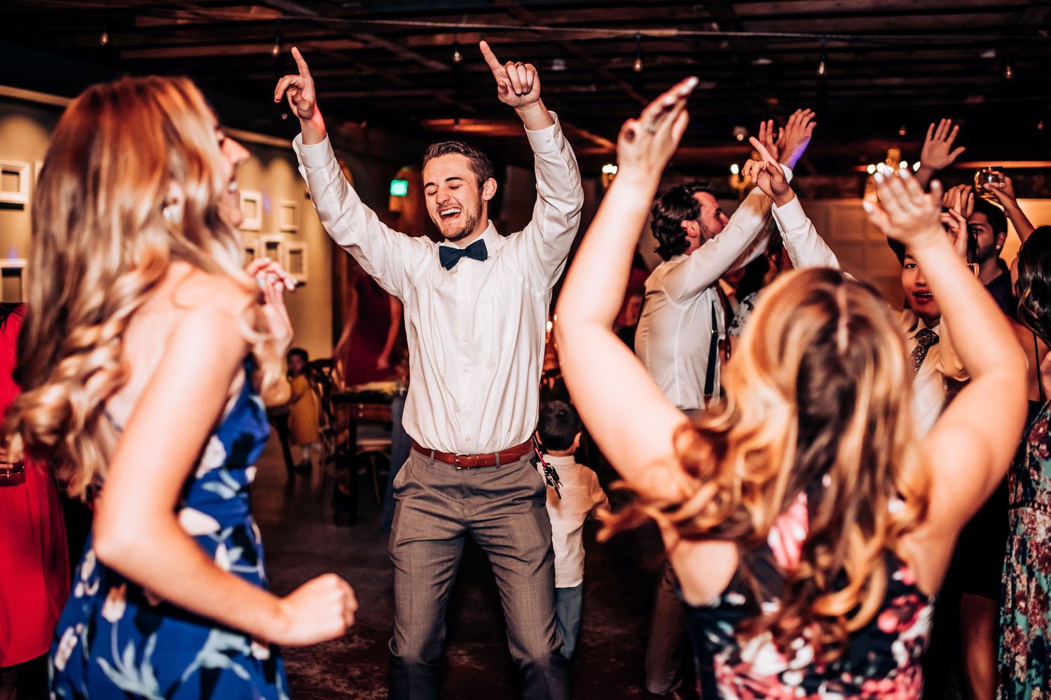 Enthusiastic dancers enjoying themselves on a wedding reception dance floor.